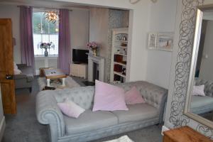 ein Wohnzimmer mit einem grauen Sofa und rosa Kissen in der Unterkunft Decimus in St. Leonards