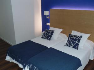 a bedroom with a large bed with blue and white pillows at Hotel Llorca in Platja de l’Almadrava