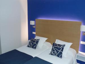 a bedroom with a bed with two pillows at Hotel Llorca in Platja de l’Almadrava
