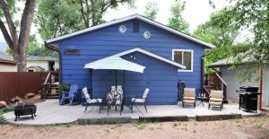 ein blaues Haus mit Stühlen und einem Sonnenschirm auf einer Terrasse in der Unterkunft 1729_ArborWay in Colorado Springs