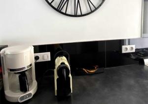 a coffee maker and a clock on a wall at Appartement spacieux centre Aix les Bains in Aix-les-Bains