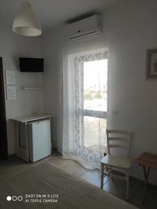 Zimmer mit einem Fenster, einem Stuhl und einem Schreibtisch. in der Unterkunft Villa Lorenza in Fasano