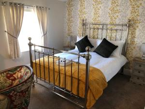 a bedroom with a bed and a chair and a window at The Black Swan Hotel in Leyburn