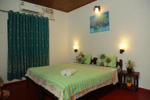 a bedroom with a bed with a green and white blanket at Marari Charlys Homestay in Mararikulam