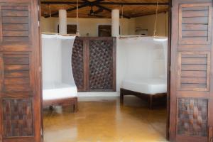 a room with two white chairs and wooden doors at Posada y Pizzeria La Termita in San Agustinillo