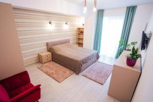 una piccola camera con letto e sedia rossa di Central Tower Apartments a Suceava
