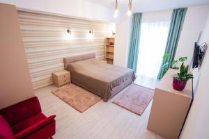 1 dormitorio pequeño con 1 cama y 1 silla roja en Central Tower Apartments, en Suceava