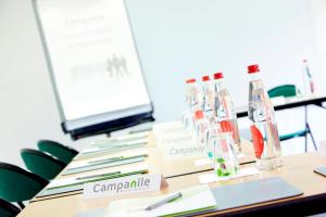 a table with a row of wine bottles on it at Campanile Rennes Ouest Cleunay in Rennes