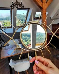 a person holding a round mirror in a room with windows at Apartament Dobre Miejsce 2 in Ustrzyki Dolne