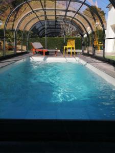 a large swimming pool with a metal roof and blue water at Villa bord de mer avec piscine et jacuzzi in Pénestin