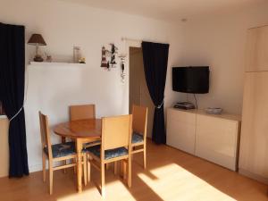 a dining room with a table and chairs and a television at Près de la mer in Le Pouliguen