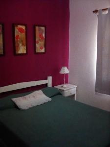 a bedroom with a green bed and a pink wall at Cabañas de Ayui in Concordia
