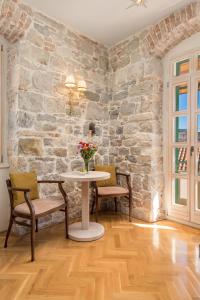 una mesa y sillas en una habitación con una pared de piedra en Captain's Guest House, en Split