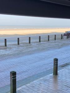 une plage avec une rangée de poteaux dans l'eau dans l'établissement appartement aan zee, à Blankenberge