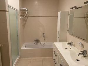 La salle de bains est pourvue d'une douche, d'une baignoire et d'un lavabo. dans l'établissement appartement aan zee, à Blankenberge