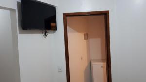 een flatscreen-tv aan een muur naast een kast bij Hotel Friburgo in Cidade Ocidental