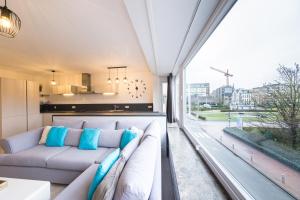 een woonkamer met een bank en een groot raam bij Ostend Center Parkview Apartment Free Parking in Oostende