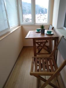 una mesa y una silla en una habitación con 2 ventanas en Apartament Mariuca en Gura Humorului