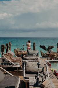 a woman sitting on a deck near the ocean at Hotelito Azul in Tulum