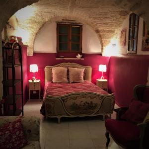 Saint-DrézéryにあるLa Voûte de Lapparanのピンクの壁のベッドルーム1室、ベッド1台(ランプ2つ付)