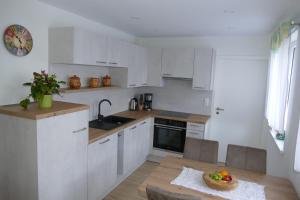 a kitchen with white cabinets and a bowl of fruit on a table at Gästehaus Hofmann - 4 Sterne Ferienwohnung Sorbitztal in Rohrbach +24 photos