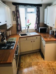 a kitchen with white cabinets and a sink and a window at New for 2021 Welcome to Violet Cottage in Combe Martin