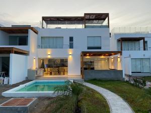 a white house with a swimming pool in front of it at Casa en Nuevo Paracas in Paracas