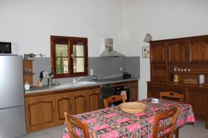 cocina con mesa y nevera blanca en Le Pailler de la Planque, en Camplong