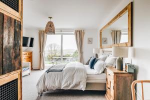 ein Schlafzimmer mit einem großen Bett und einem großen Spiegel in der Unterkunft The Gate Cornwall in Looe