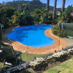 una piscina con terraza y un patio con una silla en Hahei Bed and Breakfast, en Hahei