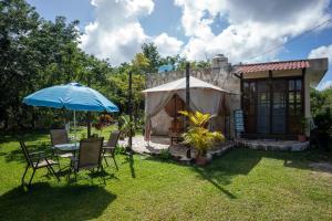 科蘇梅爾的住宿－Aldea Isla Sagrada，院子里的桌子和椅子以及雨伞