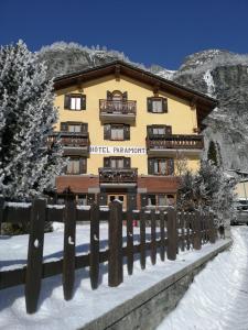 a building with a fence in the snow at Hotel Paramont in Valgrisenche