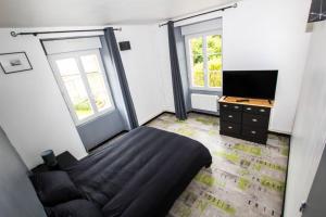 a bedroom with a bed and a tv and a couch at La Maison réseau Cycle et Gites in Clécy