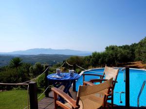 une table bleue et des chaises sur une terrasse avec piscine dans l'établissement Villa Papoura Homeleader, à Delimanolianá