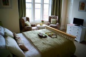 a bedroom with a bed and a tv and a window at Sunset Guest House in Hunstanton