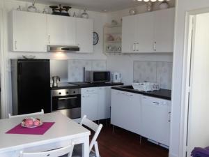 a kitchen with white cabinets and a white table at Le Pont de l'Aure in Isigny-sur-Mer