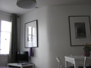 a living room with a table and a tv on a wall at Le Pont de l'Aure in Isigny-sur-Mer
