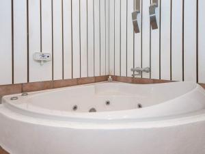 a white bath tub in a bathroom with striped walls at Holiday home Sjølund XVI in Sjølund