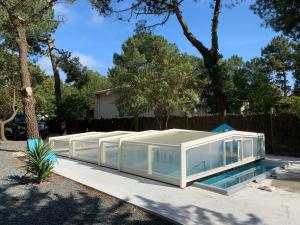 a glass house with a swimming pool in a yard at Les studios de l'Océan in Les Mathes