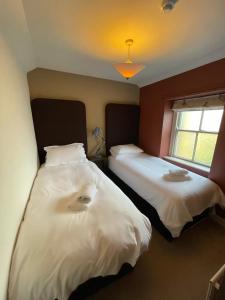 two beds in a room with white sheets at Queens Arms Litton in Litton
