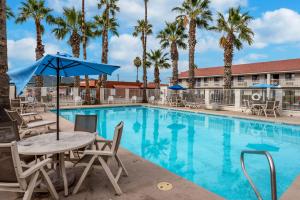 a pool with tables and chairs and palm trees at Motel 6-Eloy, AZ - Casa Grande in Eloy