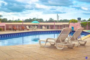 Dos tumbonas sentadas junto a una piscina. en Pousada do Recanto Feliz, en Torres