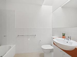 a white bathroom with a toilet and a sink at Charming Beach Home with Plenty of Outdoor Spaces in Avoca Beach