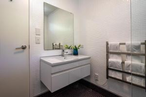 a white bathroom with a sink and a mirror at Bluebelle - Stay Waiheke in Oneroa