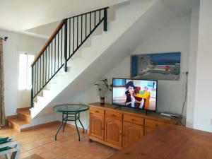 una sala de estar con TV en una cómoda de madera en Apartamentos Los Olivos, en Conil de la Frontera