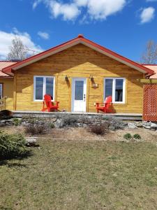 una casa amarilla con sillas rojas delante en Auberge Ma Maison, en Sainte-Melanie