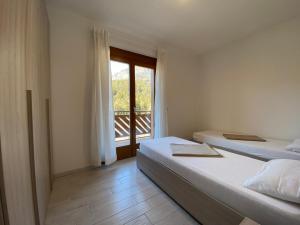 1 Schlafzimmer mit 2 Betten und einem Balkon in der Unterkunft Residenza al Parco Termale - Comano Terme in Comano Terme