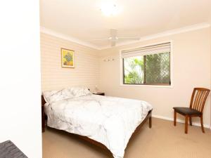 a bedroom with a bed and a window and a chair at Jade Gardens Pet Friendly in Hawks Nest