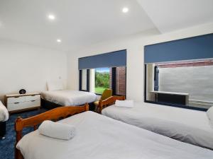 a room with three beds and a window at Beachfront Delight - 14b Bareena Avenue in North Avoca