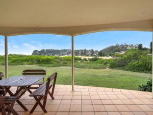a patio with a table and chairs and a view of a field at Beachfront Delight - 14b Bareena Avenue in North Avoca